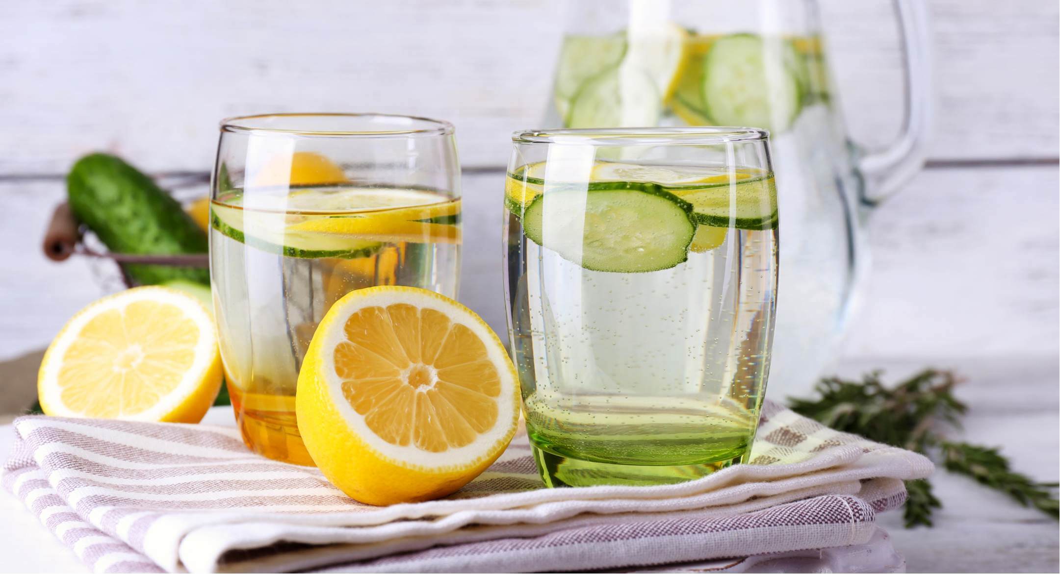 Image of glasses of water with lemons and cucumber, to aid in detoxification through infrared sauna use.