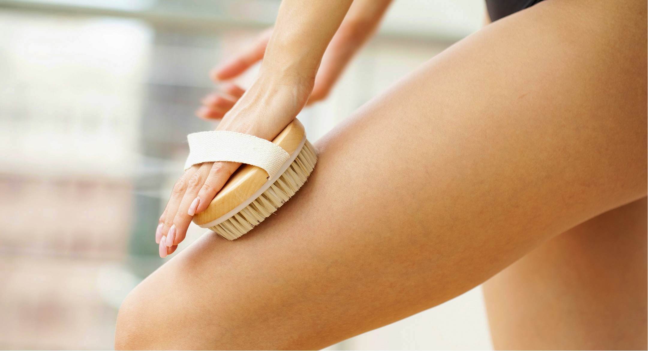 Image of woman brushing her skin with a soft brush to help manage reinvigorate her skin's appearance.